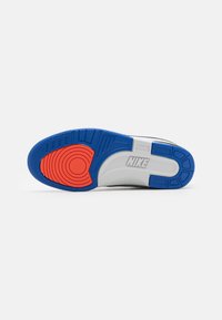 Suela de zapatilla Nike con una base de goma azul, un acento circular rojo y una media suela blanca texturizada con patrones hundidos.