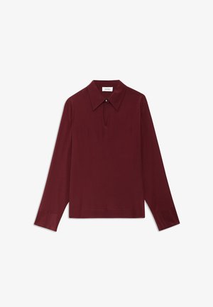 Burgundská blůza s dlouhým rukávem, s špičatým límcem, detaily ve tvaru klíčové dírky na krku a hladkou texturou. Obsahuje knoflíkové akcenty na límci.