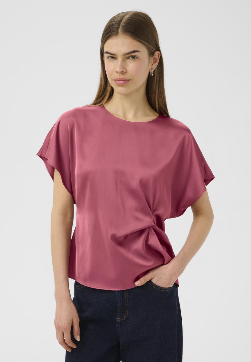 Blusa di seta rosa con scollatura rotonda e maniche larghe, caratterizzata da una vestibilità morbida e un leggero dettaglio torcigliato in vita.