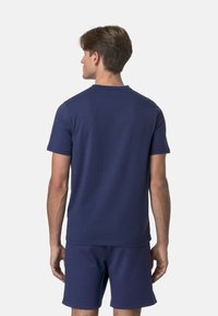 T-shirt blu navy a maniche corte realizzato in tessuto morbido. Presenta un collo a giro e una vestibilità rilassata, abbinato a pantaloni corti coordinati.