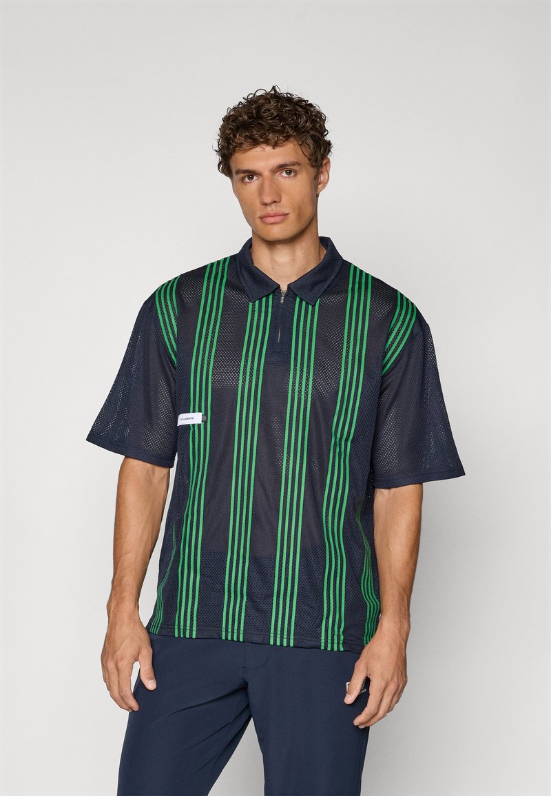 Marine mesh polo skjorte med grønne vertikale striper, hals med halv glidelås og korte ermer. Inkluderer en liten hvit etikett foran.