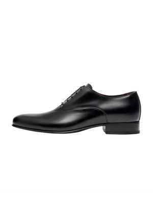 Chaussure de costume en cuir noir avec une finition lisse, bout arrondi, design minimaliste et lacets fins. Dotée d'un talon bas empilé.