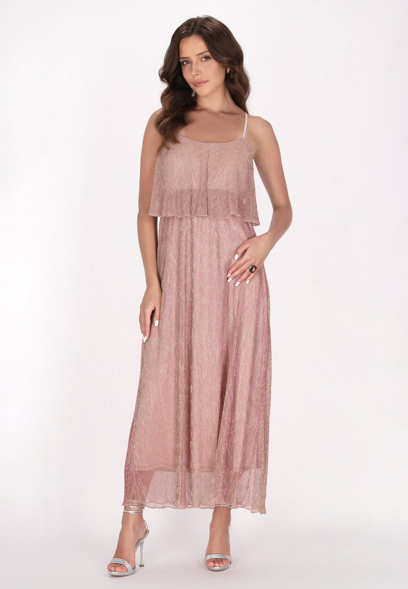 Rochie maxi dintr-un material roz deschis, cu un top stratificat, bretele fine și o textură strălucitoare. Asortată cu sandale cu toc înalt argintii.