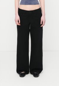 Μαύρα τζιν με φαρδιά μπατζάκια και ψηλή μέση, κλείσιμο με κουμπιά και μπροστινές τσέπες. Κατασκευασμένα από τζιν ύφασμα, με καθαρή, λεία υφή.