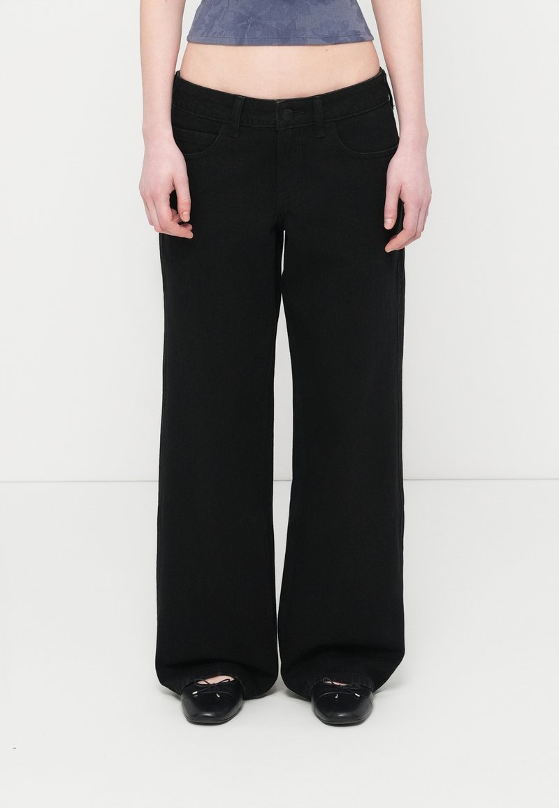 Μαύρα τζιν με φαρδιά μπατζάκια και ψηλή μέση, κλείσιμο με κουμπιά και μπροστινές τσέπες. Κατασκευασμένα από τζιν ύφασμα, με καθαρή, λεία υφή.