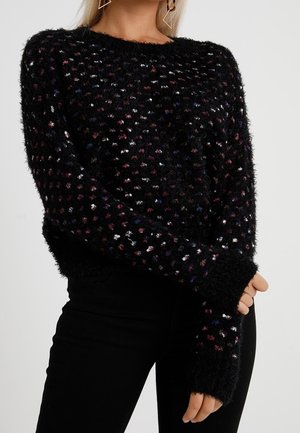 Svart, fluffig tröja med flerfärgade små prickar, rund halsringning och långa ärmar med ribbade ärmslut. Mjuk textur och avslappnad passform.