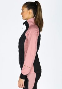 Leichte Pufferjacke mit tailliertem Schnitt. Schwarzer Körper, pinke Ärmel und goldene Akzentlinien. Verfügt über einen hohen Kragen und einen Reißverschluss.
