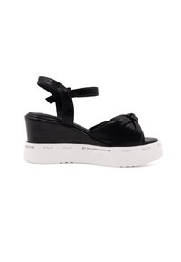Sandali wedge in pelle nera con dettaglio anteriore annodato, cinturino alla caviglia regolabile e suola piattaforma bianca con logo del marchio.