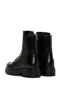 Bottes noires en cuir pour la cheville avec un devant à lacets, des fermetures éclair latérales, des semelles épaisses en caoutchouc et des accents texturés. Surface lisse avec une finition brillante.