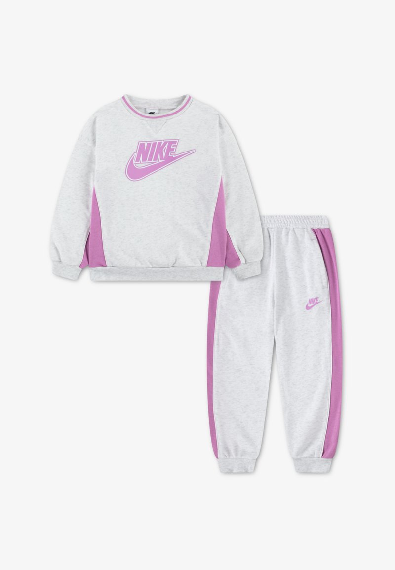 Σετ γκρι βαμβακερού φούτερ και παντελονιού με ροζ πλαϊνές ρίγες και λογότυπο Nike. Το φούτερ έχει ριμπ μανσέτες· το παντελόνι έχει ελαστική μέση.
