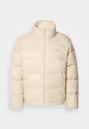 Beige puffer jacket with a high collar, zip closure, and two side pockets. Features a quilted design and soft, smooth texture.