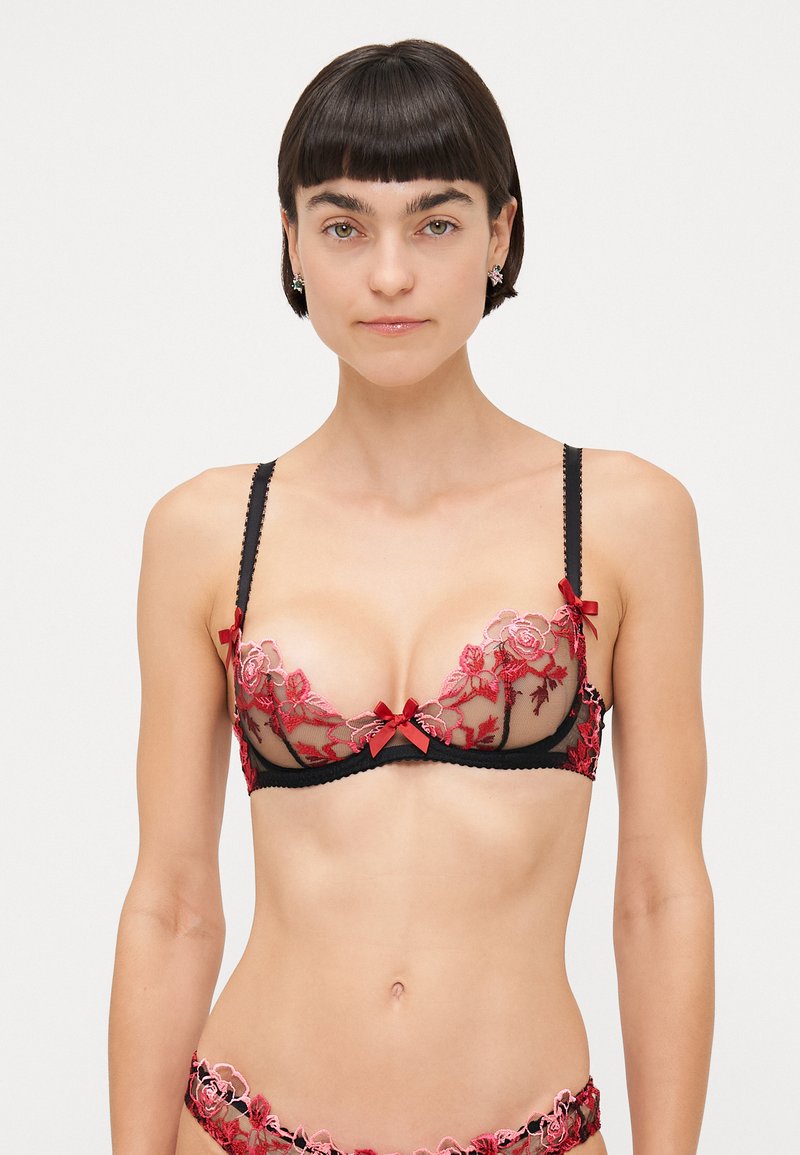 Soutien-gorge en dentelle noire avec broderies florales rouges et nœuds. Design transparent avec des détails raffinés, bretelles réglables et bords festonnés.
