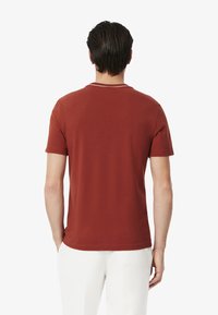 T-shirt in cotone rosso con maniche corte, caratterizzata da un design semplice e un collo rotondo. Nessun motivo o dettaglio visibile.