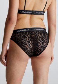 Svarte blonde truser med stripemønster, med et elastisk liv med Calvin Klein-merke. Stretchstoff og gjennomsiktig tekstur.
