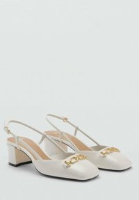 Talons de slingback blancs avec un bout carré, accent en chaîne dorée et un talon bloc modéré. Matériau lisse avec un intérieur neutre.