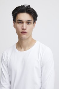 Fehér hosszú ujjú ing modellen, lekerekített nyakkivágással és sima pamut textúrával, semleges háttérrel.