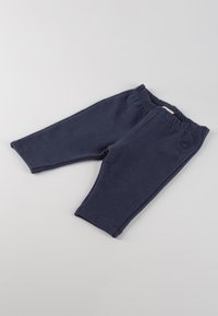 Pantaloni da jogging per bambini blu navy con vita elasticizzata, posati su una superficie grigia chiara.