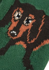Tissu tricoté mettant en vedette un design de dachshund en marron et beige sur un fond vert. Les détails notables comprennent des yeux expressifs et un tricotage texturé.