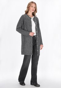 Cardigan tricotat gri, cu închidere cu nasturi, având o textură interesantă și accente decorative cu mărgele de-a lungul gâtului. Mâneci lungi.