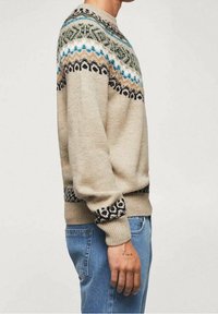 Pull en tricot beige avec des motifs fair isle multicolores en bleu, vert et noir au niveau du col, des manches et de l'ourlet. Design ajusté.