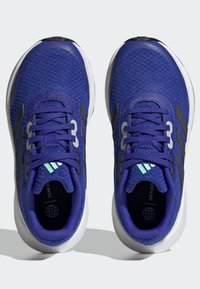 Scarpe da atletica viola con tomaia testurizzata, dettagli neri e suole bianche. I lacci e il marchio presentano dettagli riflettenti.