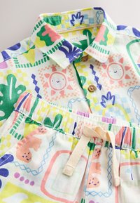 Buntes Baumwolloutfit bestehend aus einem Hemd mit Kragen und Knöpfen sowie gemusterten Shorts mit verspielten Grafiken und elastischem Bund.