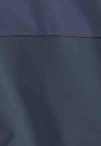 Ύφασμα δίχρωμο με ανοιχτό μπλε πάνελ στην κορυφή και σκουρότερο μπλε πάνελ από κάτω, που δείχνει ελαφριές πτυχώσεις και διαφορές υφής.