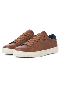 Brown leather sneakers with white rubber soles, round toe, flat laces, and subtle accents in blue and red on the side. Textured surface.