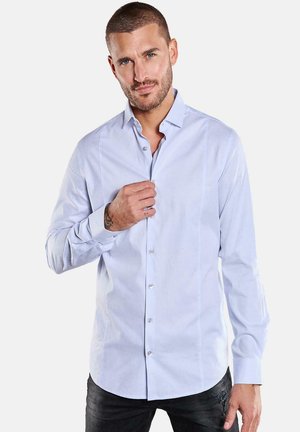 Hellblaues Hemd mit Knöpfen, lange Ärmel, glatter Stoff, dezente vertikale Streifen, mit einem Kragen und vorderen Knöpfen, getragen mit dunklen Jeans.