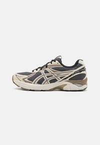 Black and beige athletic shoes with mesh and synthetic upper, featuring a curved sole, contrasting accents, and a lace-up design.