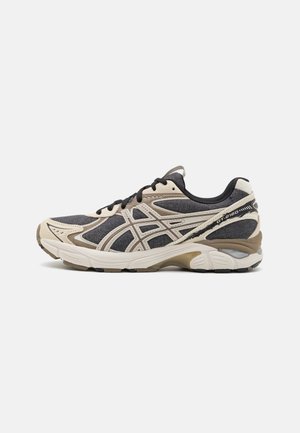 Black and beige athletic shoes with mesh and synthetic upper, featuring a curved sole, contrasting accents, and a lace-up design.