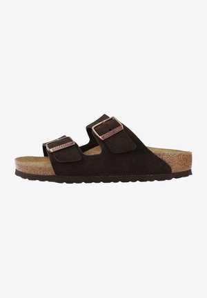 Dark brown suede sandals with two adjustable straps, metal buckles, and a cork footbed. Flat sole with textured grip.