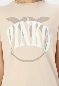 Bežinis trumpaeigiai marškiniai su dideliu baltu ir pilku "PINKO" teksto grafiniu vaizdu, papuoštu drugelių akcentais viršnėje. Minkšta medvilnė.