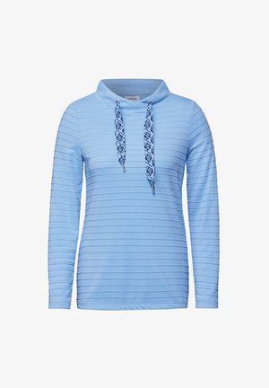 Hellblaues Langarmoberteil mit Kragen, das eine horizontale Rippstruktur sowie gemusterte Kordeln mit silbernen Spitzen aufweist.