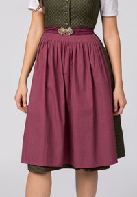 Traditionelles Kleid mit einem enganliegenden grünen Oberteil mit einem Rautenmuster und einem fließenden burgunderfarbenen Rock mit vertikalen Streifen. Dekorative Schnalle an der Taille.