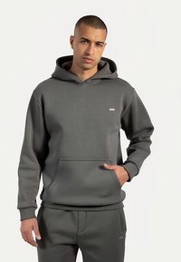 Sweat à capuche gris foncé en tissu doux, doté d'une poche kangourou centrale, de poignets côtelés et d'un petit logo sur la poitrine.