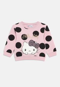 Sweatshirt rosa com grandes bolinhas pretas. Apresenta um gráfico da Hello Kitty com um laço com bolinhas. Punhos e bainha canelados. Textura de tecido macio.