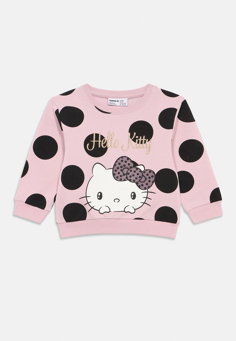Sweatshirt rosa com grandes bolinhas pretas. Apresenta um gráfico da Hello Kitty com um laço com bolinhas. Punhos e bainha canelados. Textura de tecido macio.