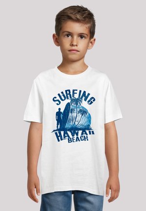 White t-shirt featuring blue surfing graphic with palm trees and "HAWAII BEACH" text, round neckline, short sleeves, and relaxed fit.