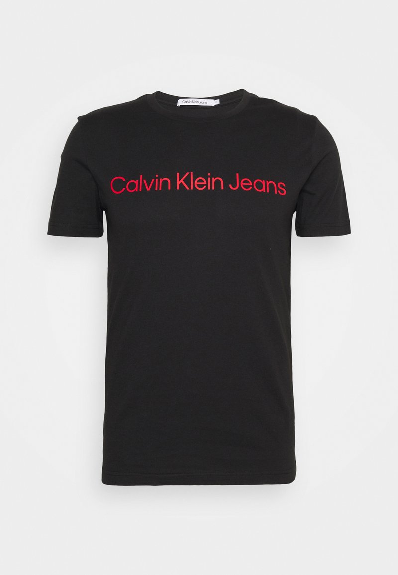 Čierne tričko s krátkym rukávom a okrúhlym výstrihom s červeným nápisom "Calvin Klein Jeans" na prsiach.