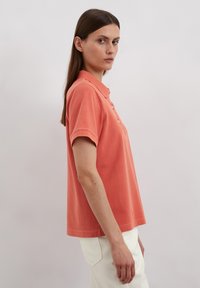Koraalrode polo shirt met korte mouwen, voorzien van een klassieke kraag en een drie-knopen sluiting, gemaakt van zacht katoen.