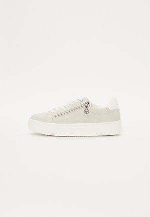 Sneaker di camoscio beige con suola in gomma bianca, dotata di una cerniera laterale e hardware circolare in argento. Chiusura con lacci standard nella parte frontale.