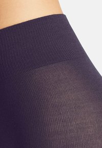 Leggings opachi di un viola scuro con un motivo a coste testurizzato e una cintura liscia e solida; il tessuto elasticizzato offre comfort e vestibilità.