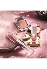 Ensemble de maquillage KIKO Milano comprenant un blush compact, un rouge à lèvres liquide et un flacon de fond de teint sur un fond pailleté rose avec une pochette à motifs.