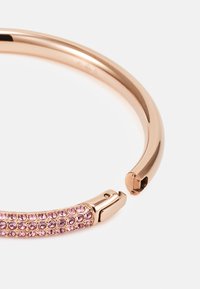 Náhrdelník z ružového zlata s hladkým kovovým povrchom a sekciou zdobenou ružovými okrúhlymi kryštálmi pre väčšiu ozdobu.