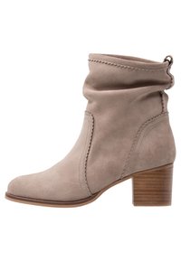 Bottine en daim gris clair avec un design décontracté, des accents cousus et un talon carré en bois. Bout arrondi et texture lisse.