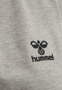 Grå bomullstyg med en slät textur har en svart broderad logotyp av en bi och ordet "hummel" nedanför.