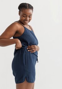 Marineblaue, ärmellose Romper aus strukturiertem Stoff, mit verstellbarem Kordelzug in der Taille und abgerundetem Saum, der eine lockere Passform bietet.