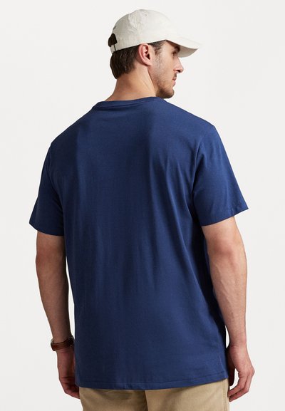 Tricou de culoare albastră marină, cu mâneci scurte și guler rotund. Textură moale și netedă. Partea din spate are o croială lejeră, fără motive sau embellismente.