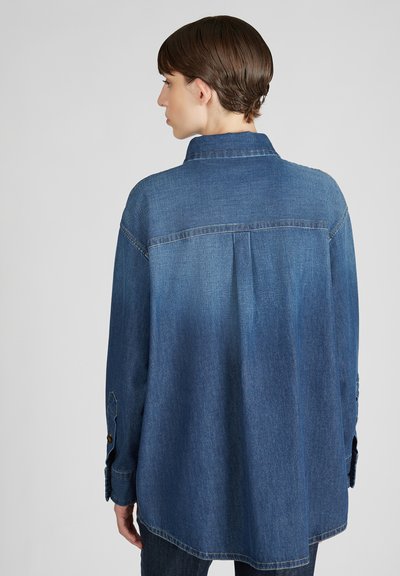 Donkerblauwe denim shirt met een kraag, lange mouwen, knoopsluiting bij de mouwen en een gebogen zoom. Heeft een pas aan de achterkant en een subtiele textuur.